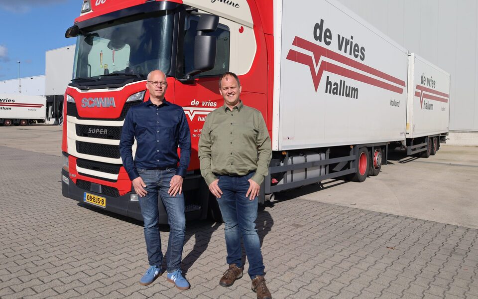 Gerrit Douwe de Vries en Benno de Vries, eigenaren van transportbedrijf De Vries Hallum, poseren voor hun vrachtwagen op het bedrijventerrein.