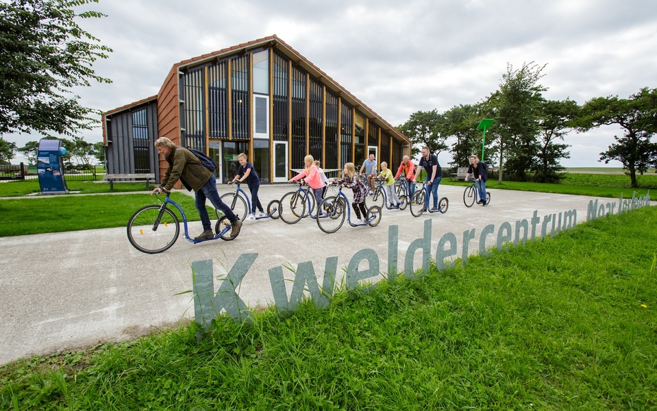 Kinderen en volwassenen stappen op hun step bij het Kweldercentrum Noarderleech in Hallum, klaar voor een avontuurlijke tocht door de natuur.