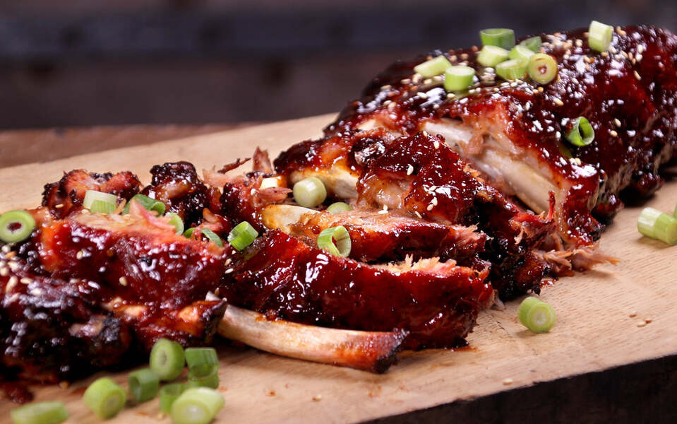 varken spare ribs dik bevleesd met bosui op een plank geserveerd