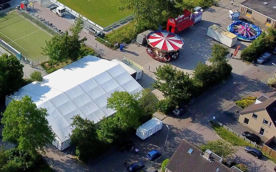 Feestterrein It Blikkelân feest dorpsfeest tent op een parkeerterrein met attracties omringd door bomen 