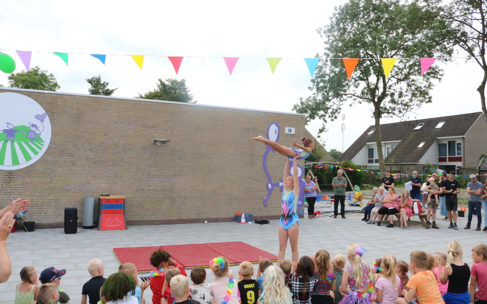acrobatiek en springen door turnsters op een schoolplein onder toeziend oog van ouders en kinderen