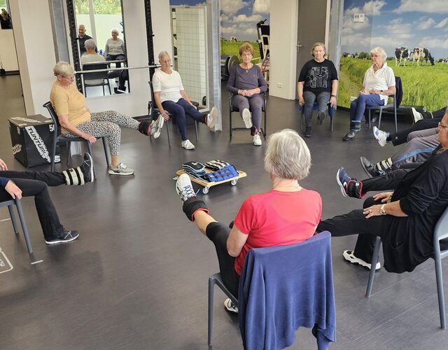 Groep oudere deelnemers doet zittende been- en balansoefeningen in een kring tijdens de valpreventietraining Ik Sta Sterk.