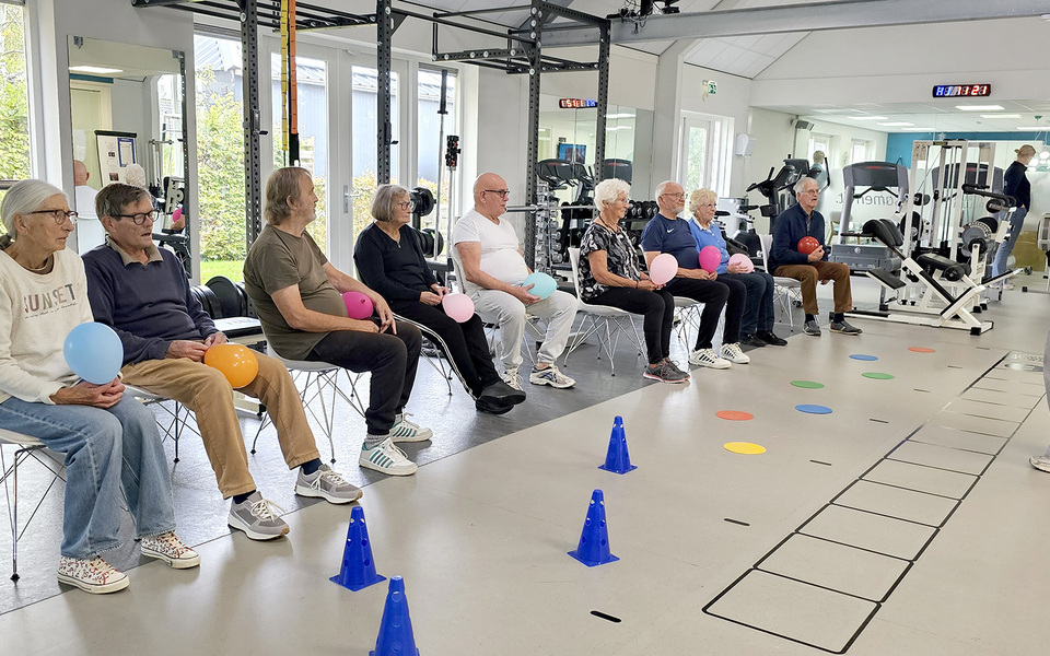 Groep oudere deelnemers doet zittende been- en balansoefeningen in een kring tijdens de valpreventietraining Ik Sta Sterk.