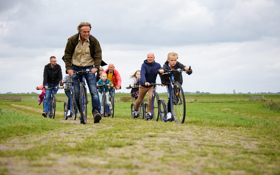 Gezinnen met kinderen steppen onder begeleiding van een natuurgids door het groene kwelderlandschap bij Noarderleech in Hallum.