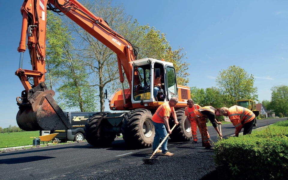 Wegwerkzaamheden met graafmachine en asfaltploeg op provinciale weg bij Stiens tijdens onderhoud N357/N398.