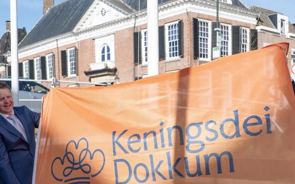Eerste Keningsdei-vlag wordt gehesen bij een woning aan de Zijl in Dokkum als start van de voorbereidingen voor Keningsdei.