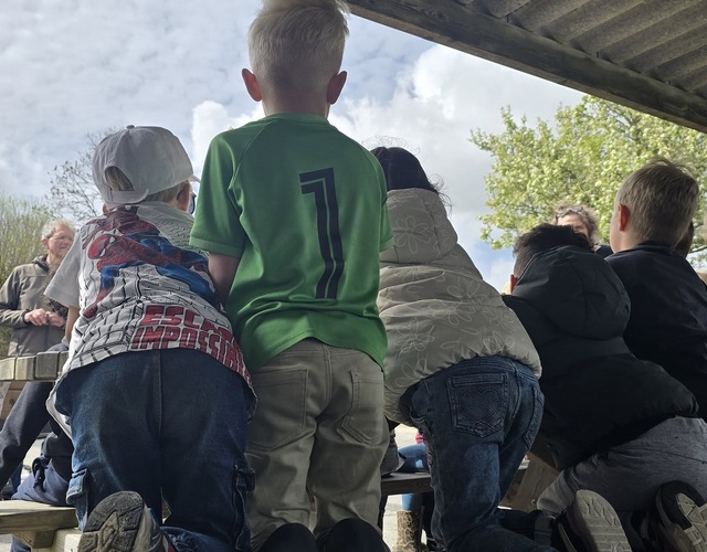 Kinderen van OBS Op ’e Dobbe kijken en luisteren aandachtig tijdens het zaaien van zonnebloemen voor Heel Hallum Bloeit 2026