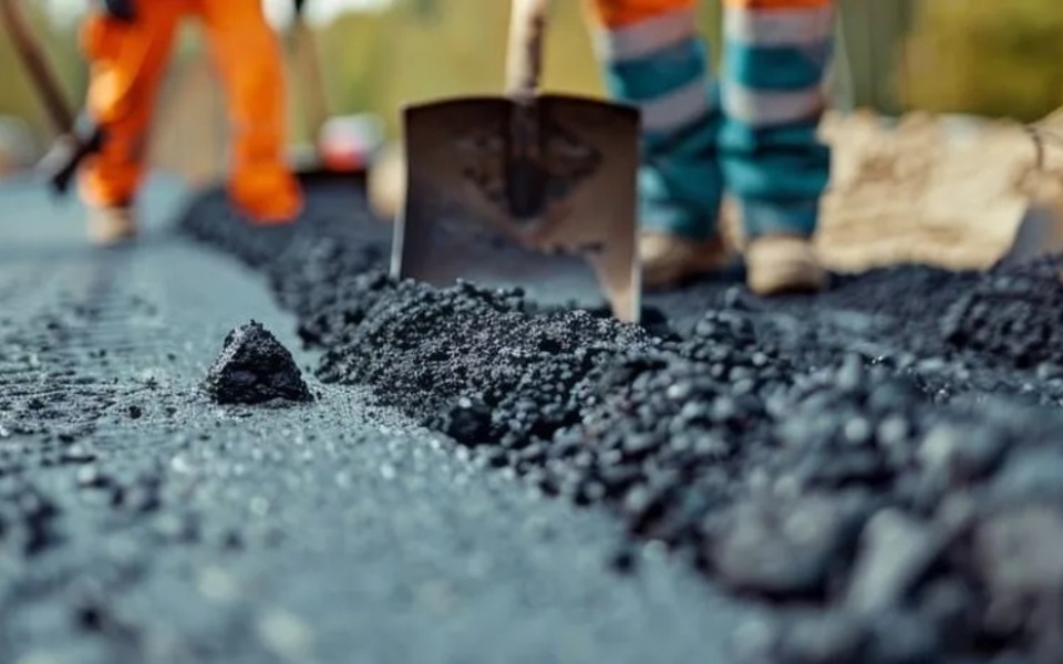 Wegwerkzaamheden aan asfaltweg met asfaltmachine en wegwerkers tijdens onderhoud aan de rijbaan.