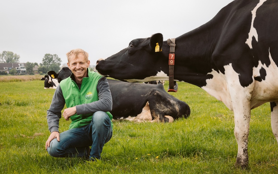 Melkveehouder poseert tussen de koeien in de wei tijdens de Campina Open Boerderijdagen.