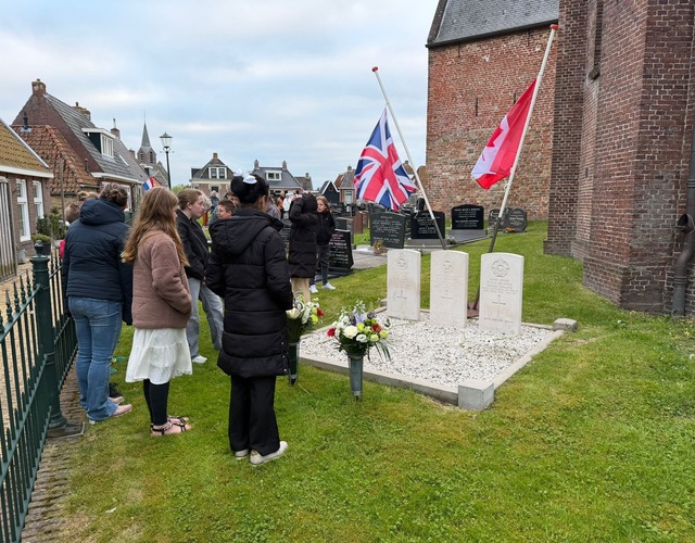 Inwoners en jongeren staan stil bij de oorlogsgraven naast de kerk in Hallum tijdens de herdenking op 4 mei 2026.
