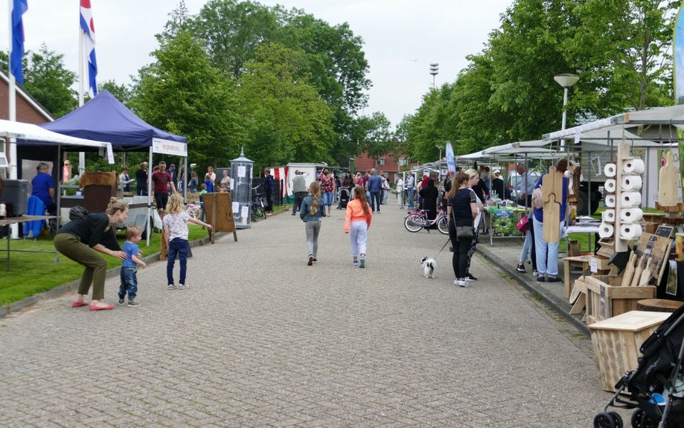 Bezoekers wandelen langs kraampjes tijdens de gezellige braderie in Hallum, met marktstands, ondernemers en activiteiten voor jong en oud.