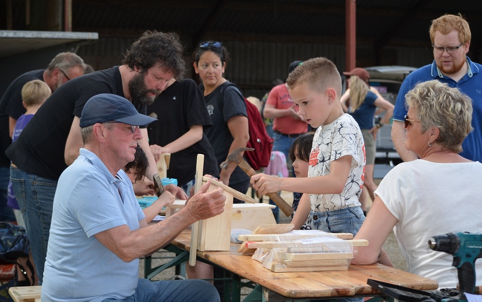 Kinderen en volwassenen timmeren samen vogelhuisjes tijdens de Jeugdfûgelwachtdei 2026 op de boerderij.