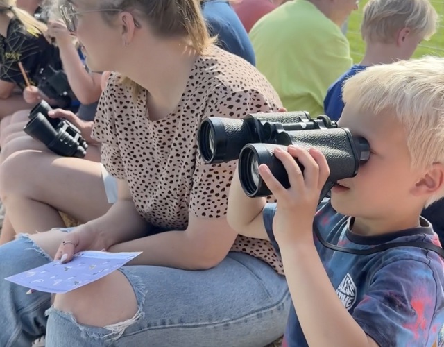 Jonge deelnemer kijkt met een verrekijker naar vogels tijdens de Jeugdfûgelwachtdei 2026.