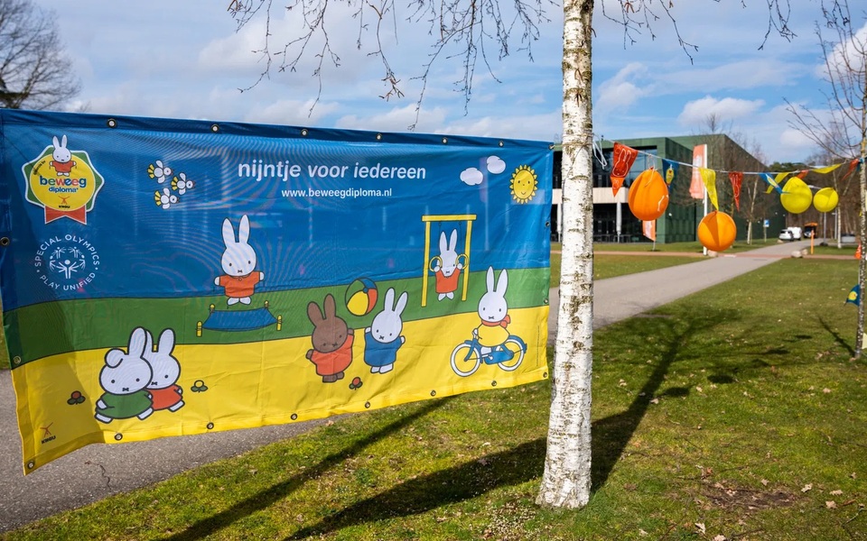 Spandoek van 'Nijntje voor iedereen' met spelende nijntje-figuren langs een wandelpad, als promotie voor het Nijntje Beweegdiploma.