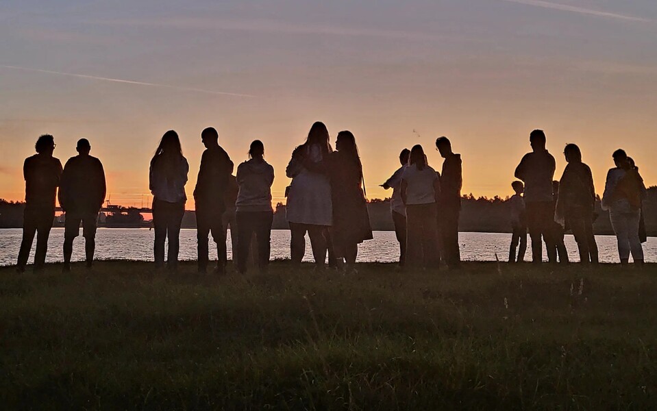 Deelnemers aan Walk into the Light wandelen bij zonsopkomst samen richting het licht om stil te staan bij suïcide en verbinding.
